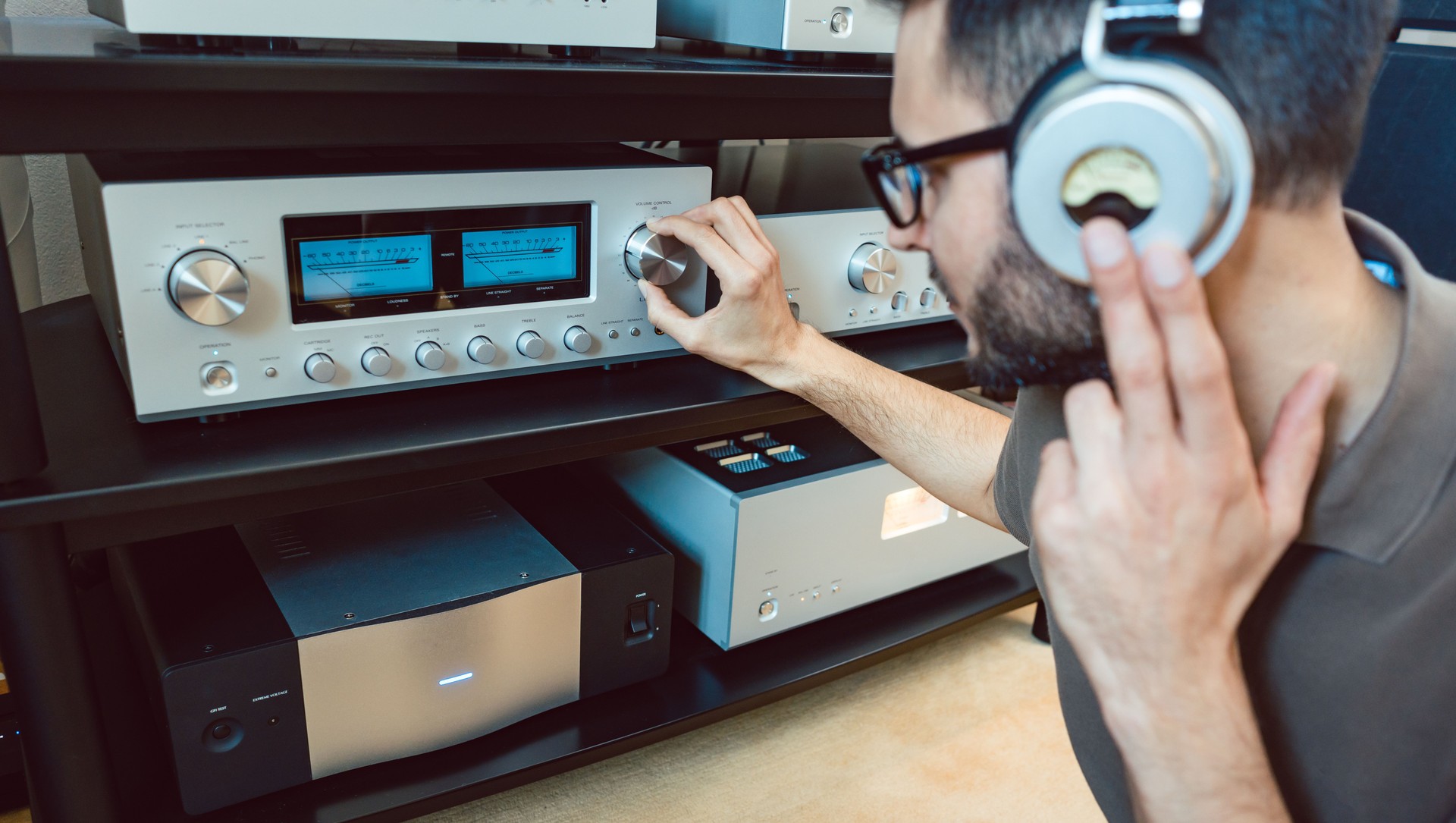Man turning up the volume on home Hi-Fi stereo